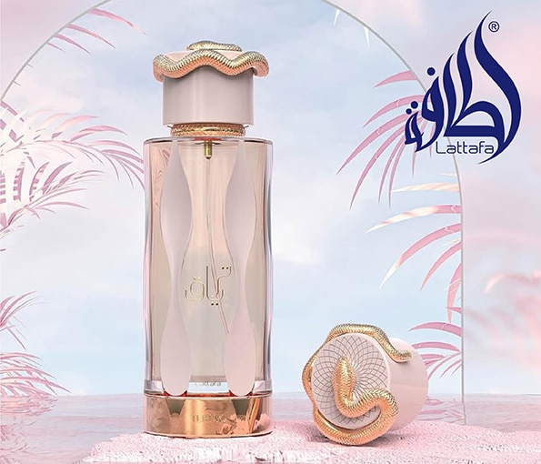 Parfumul Lattafa într-un flacon elegant alb‑auriu, prezentat pe un fundal roz pastel.